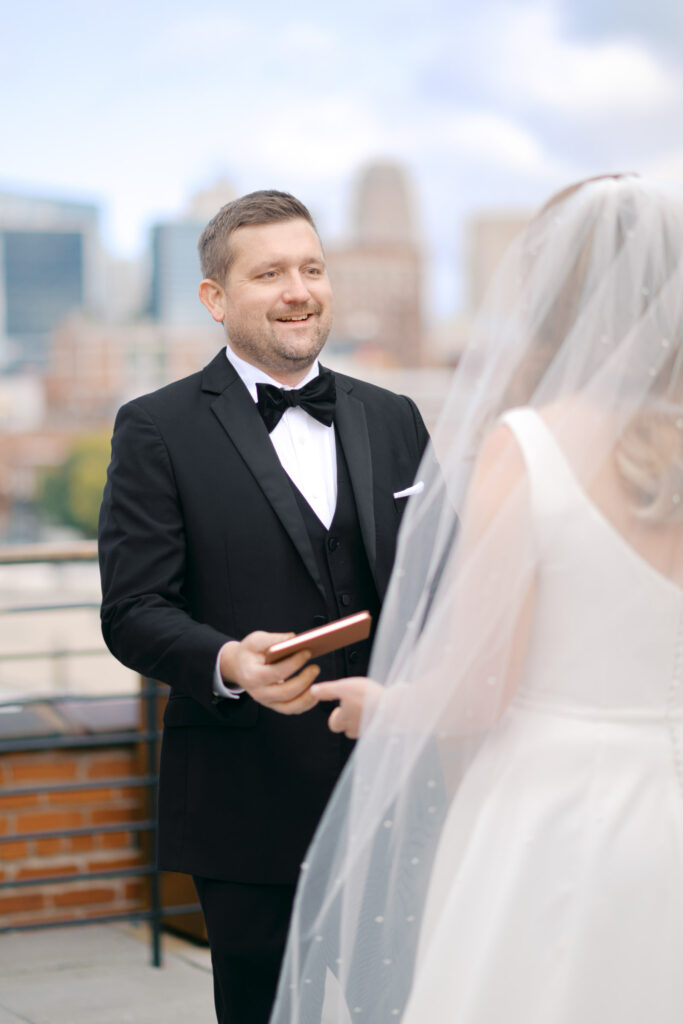 Groom holding his vows during an emotional first look on the Crossroads Hotel rooftop in Kansas City