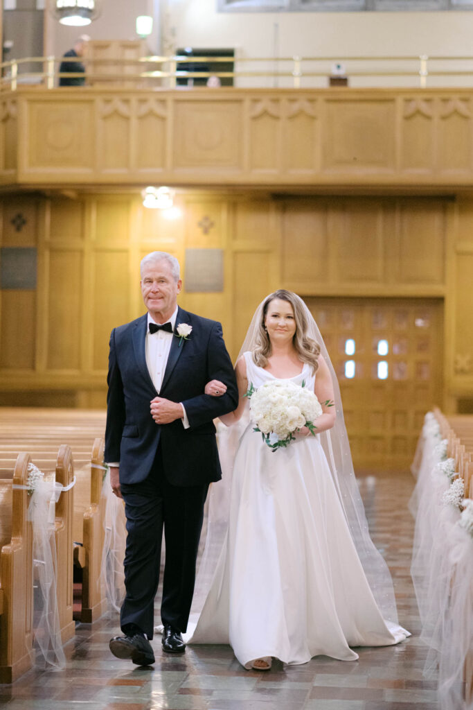 Bride walking down the aisle with her father during a classic church wedding ceremony