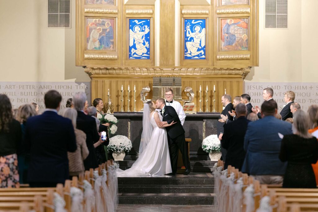 Bride and groom sharing their first kiss at the altar during a traditional church wedding ceremony