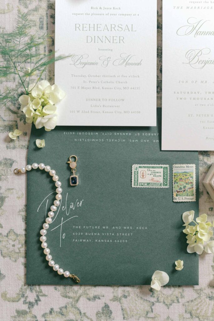 Rehearsal dinner invitation and wedding stationery details with pearl bracelet and vintage stamps