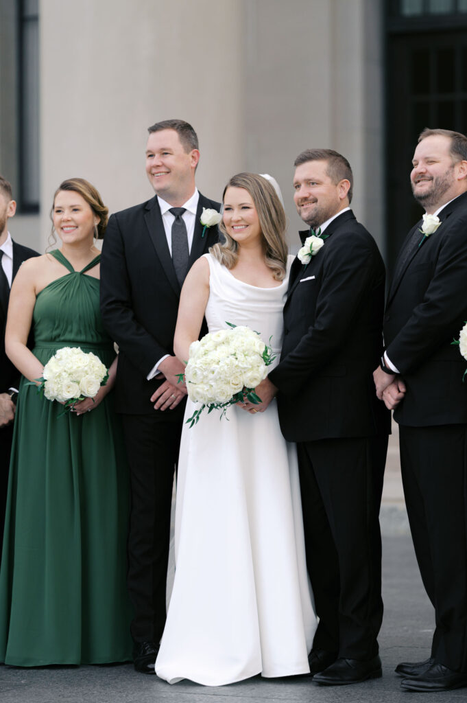 Bride and groom posing with their wedding party outside a historic Kansas City building