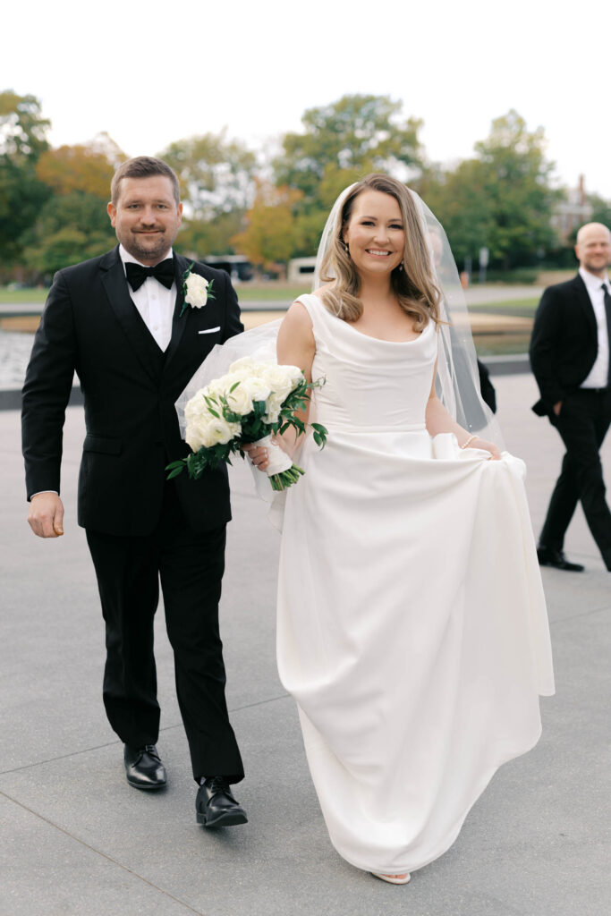 Bride and groom walking together after their ceremony with fall trees in the background