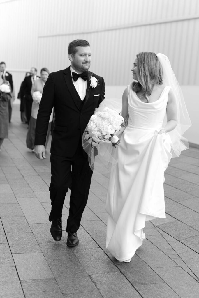 Bride and groom walking together after their ceremony with the wedding party behind them
