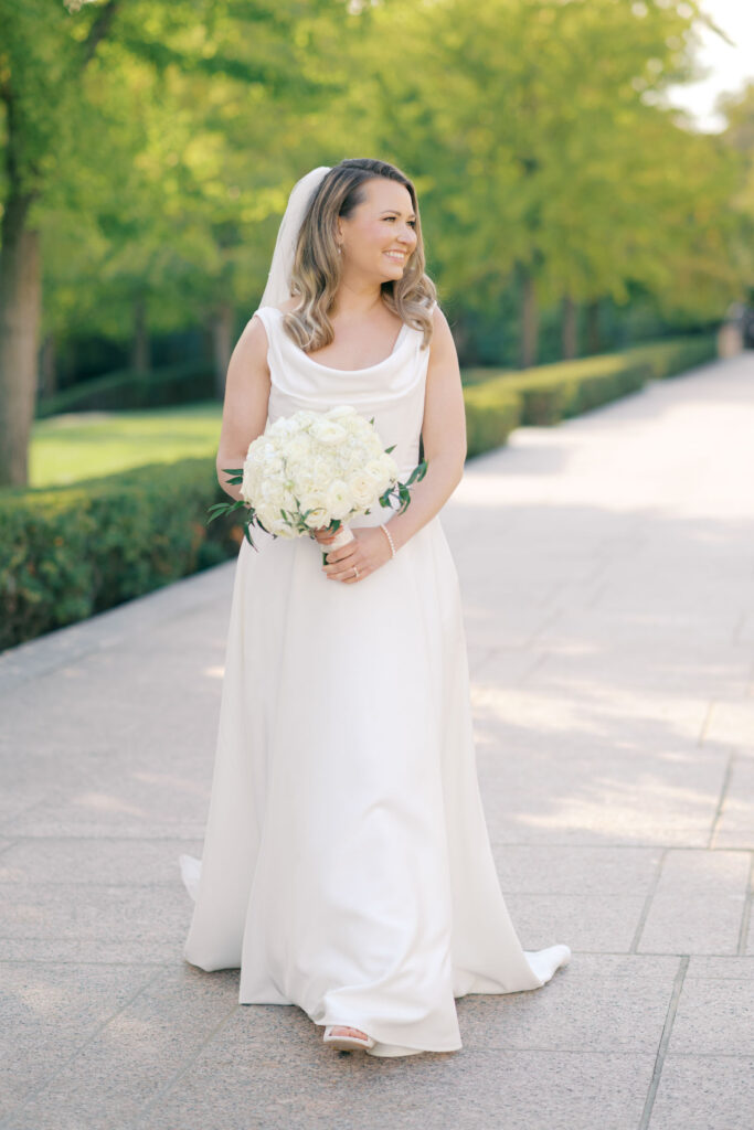 Bride holding a white rose bouquet during wedding portraits in a garden setting