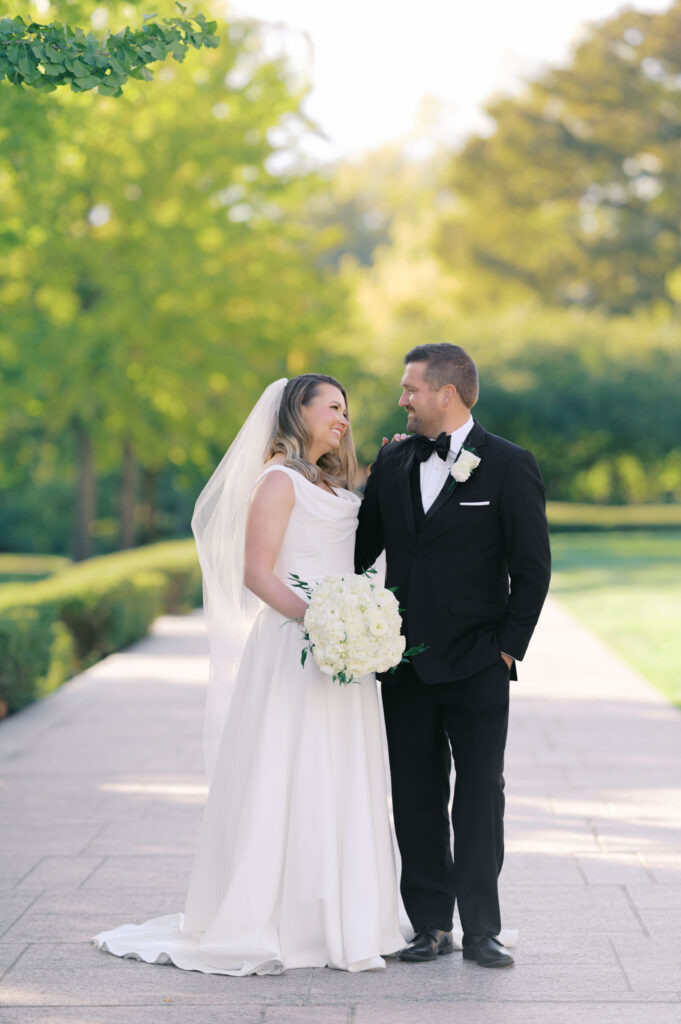 Bride and groom walking together through a garden path during wedding portraits in Kansas City