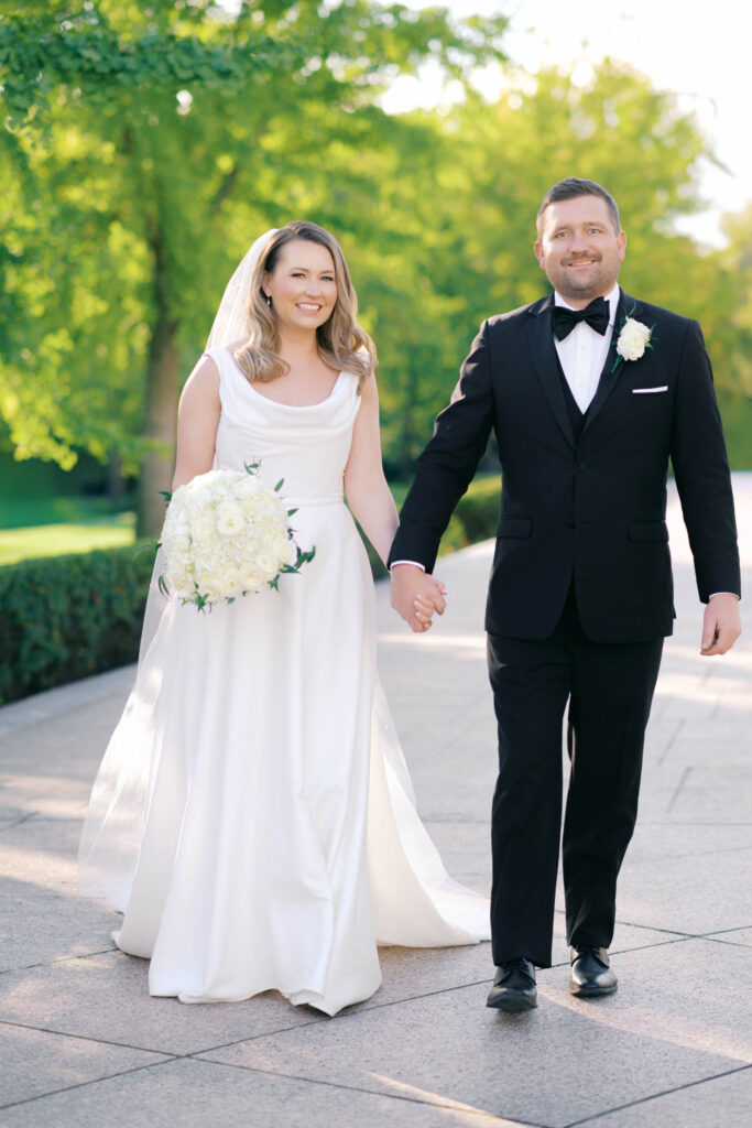 Bride and groom holding hands and walking together during golden hour wedding portraits