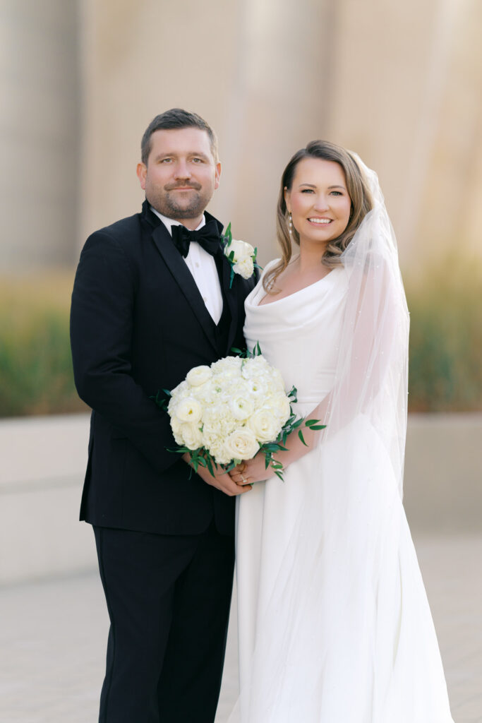 Classic portrait of bride and groom together holding a white rose wedding bouquet