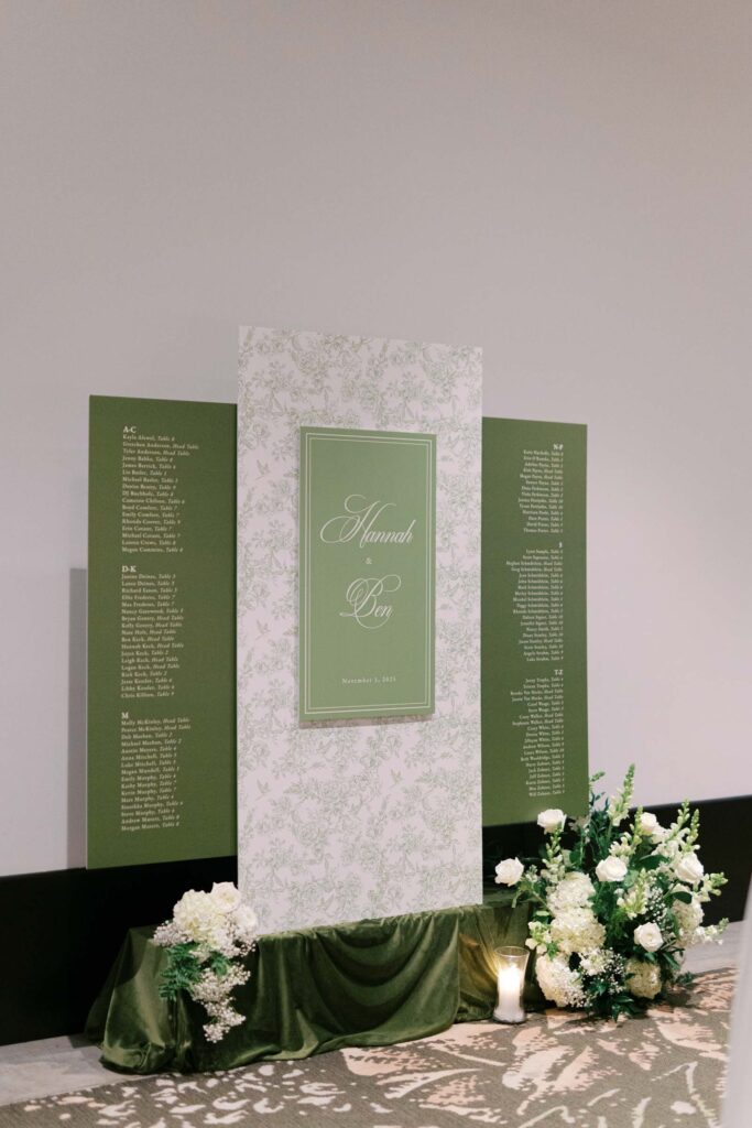 Green wedding seating chart display with floral accents and candlelight