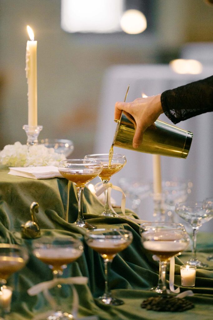 Bartender pouring espresso martinis into coupe glasses at a wedding reception