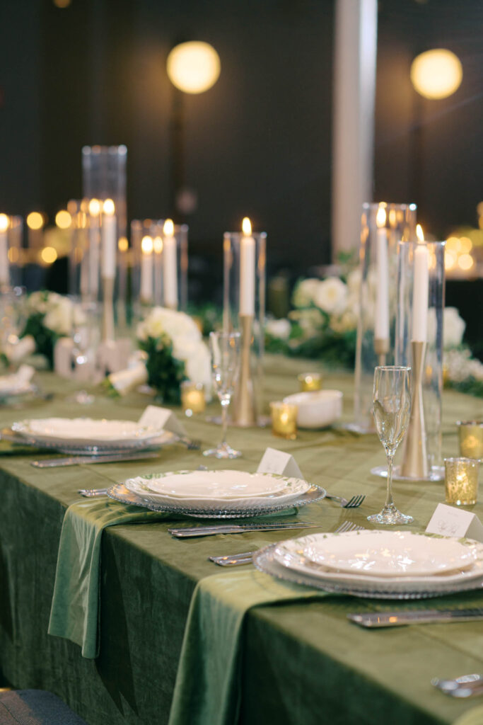 Wedding reception table with green linens, candlelight, and elegant place settings